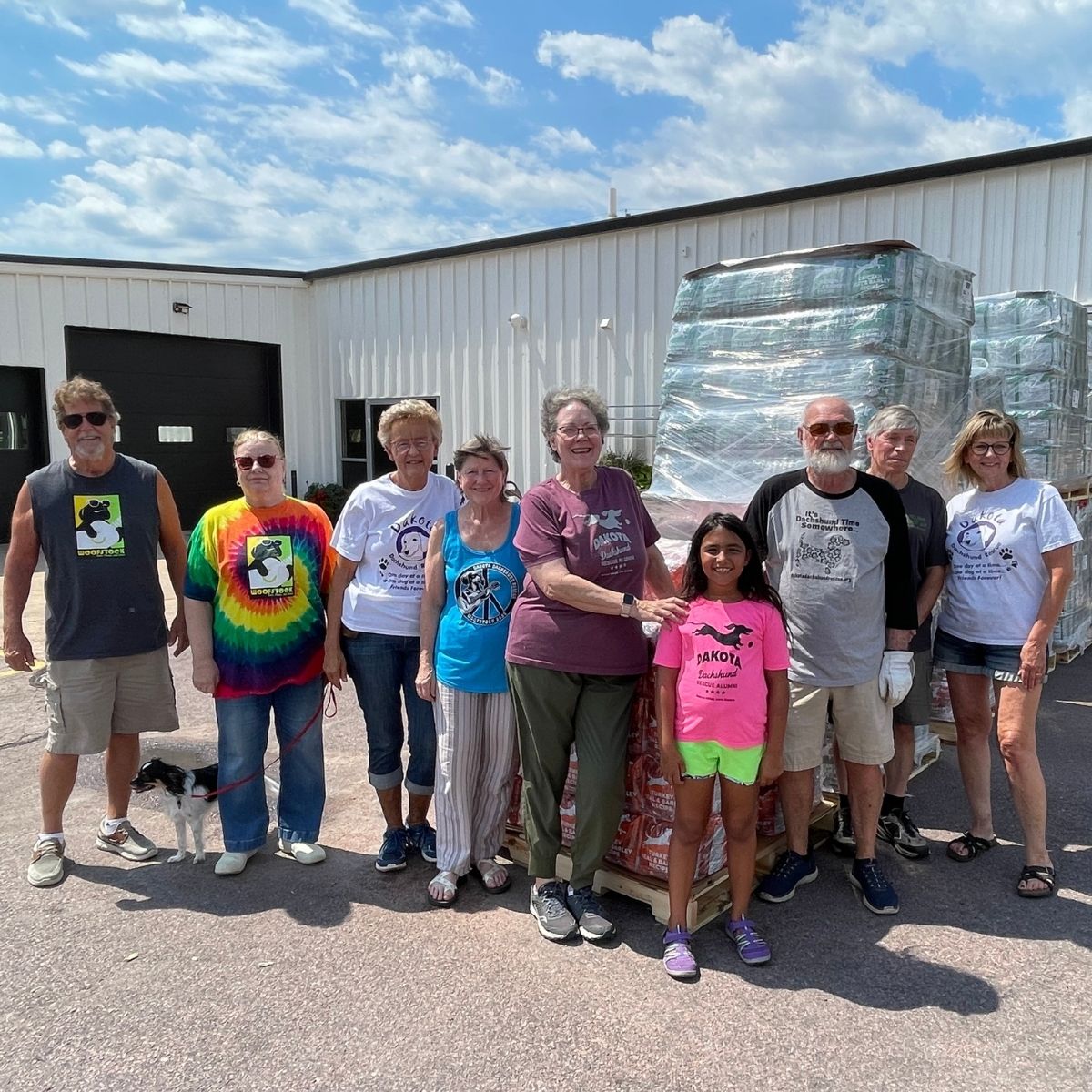 Dakota Dachshund Rescue volunteers gathered beside pallets of donated dog food outside Roxi & Co.
