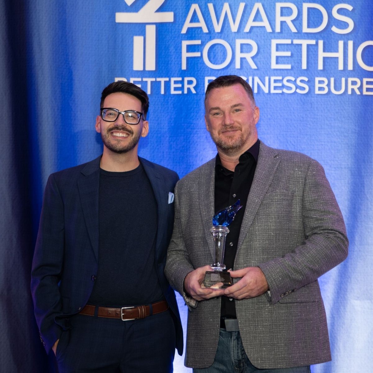 Roxi & Co owner Telly Rollinger holding the 2026 BBB International Torch Award beside another attendee at the Denver ceremony.