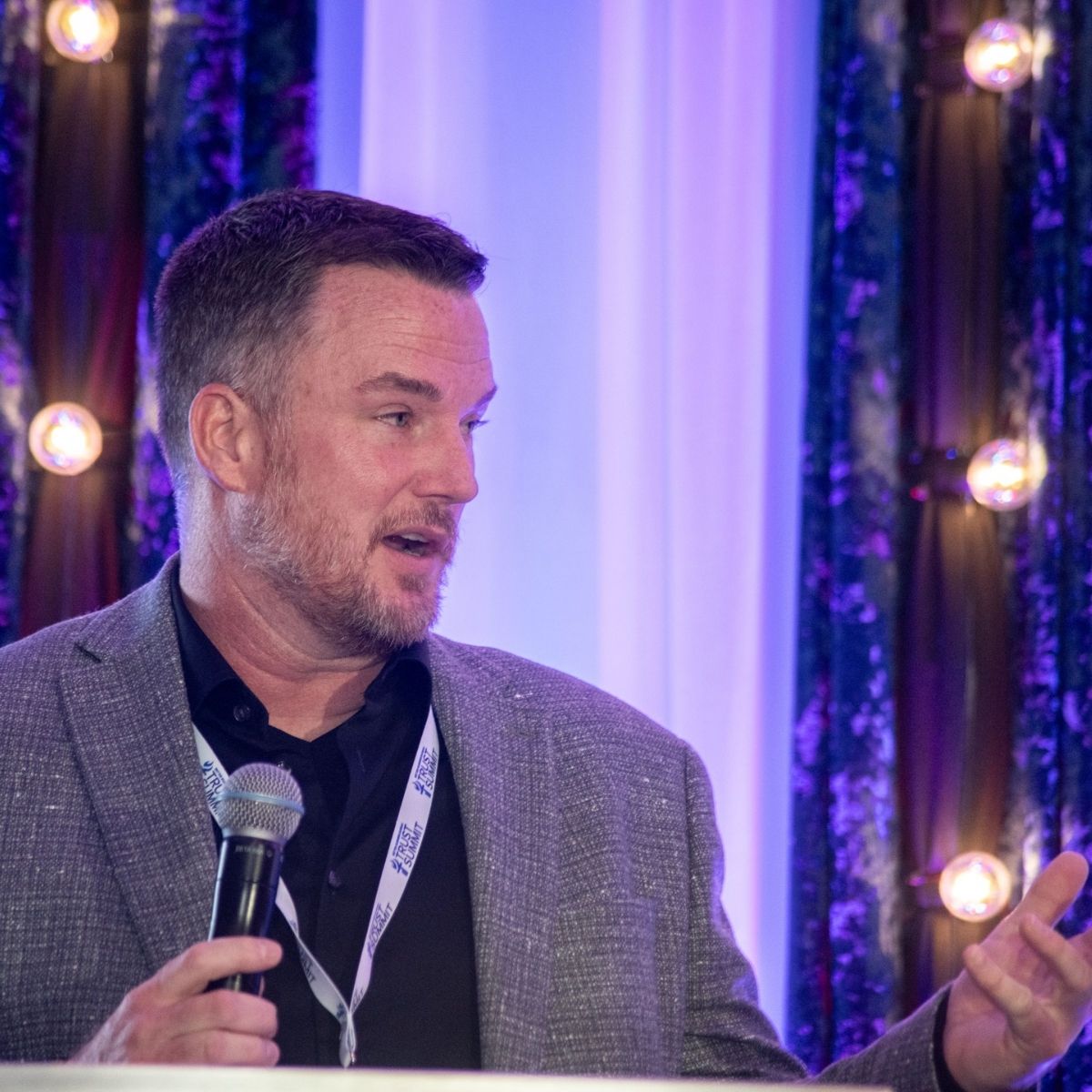 Roxi & Co owner Telly Rollinger speaking into a microphone at the 2026 BBB International Torch Award ceremony in Denver.